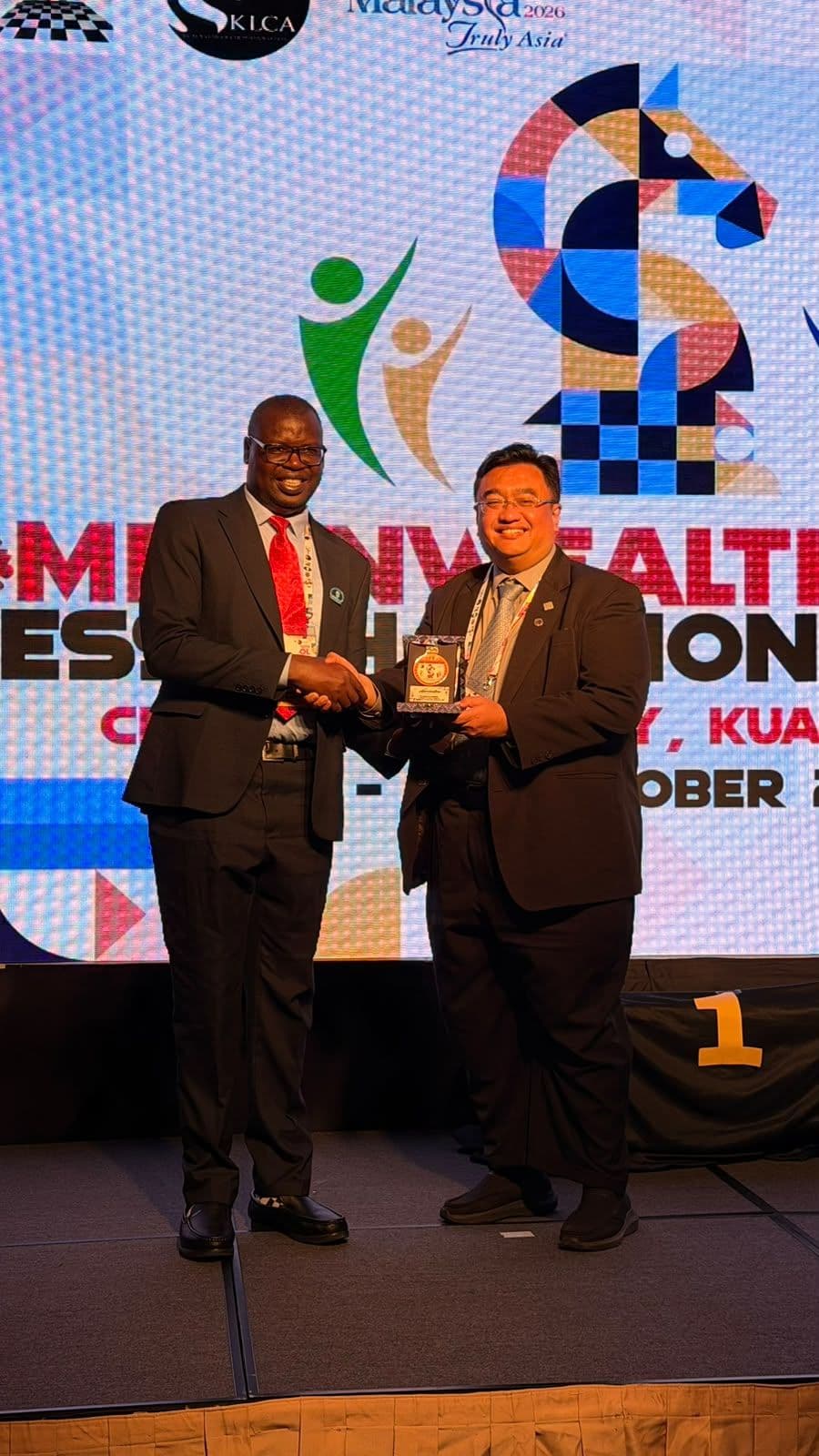 Appeals Chairman IA Benard Wanjala receives an appreciation award for the Malaysian Chess Federation President